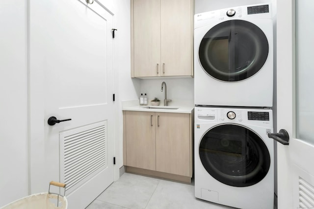 laundry room with cabinets, stacked washing maching and dryer, sink, and light tile patterned floors