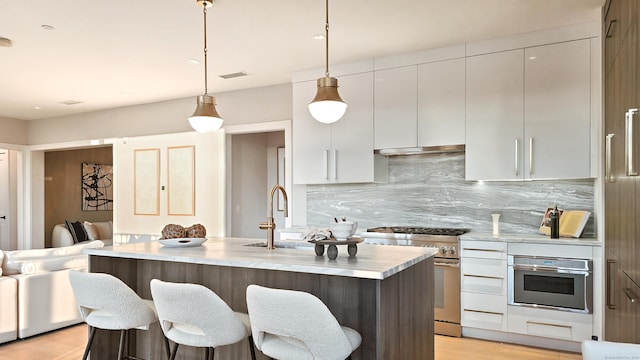 kitchen with sink, decorative light fixtures, a center island with sink, appliances with stainless steel finishes, and backsplash