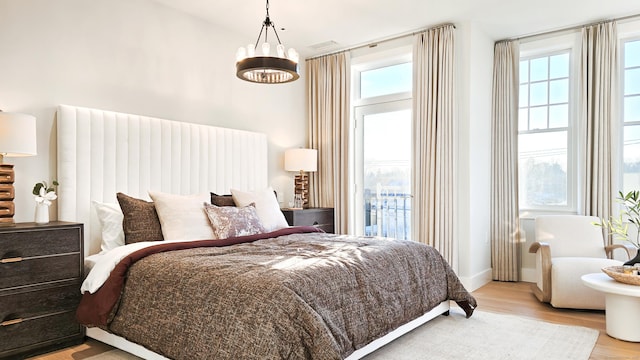 bedroom with a chandelier, light hardwood / wood-style floors, and multiple windows