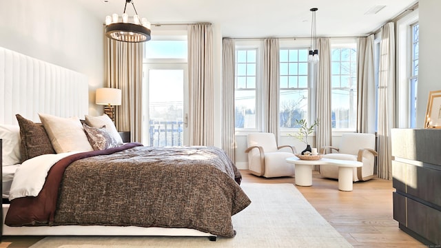 bedroom featuring multiple windows, a notable chandelier, and light wood-type flooring