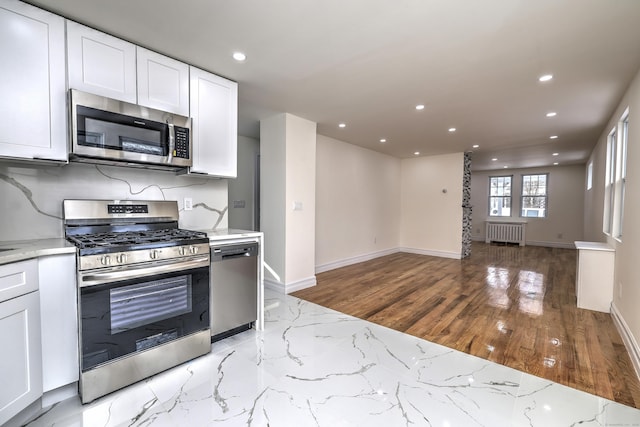 702 King St, Stratford, CT 06614 - kitchen featuring appliances with stainless steel finishes, recessed lighting, radiator, white cabinetry, and light stone countertops