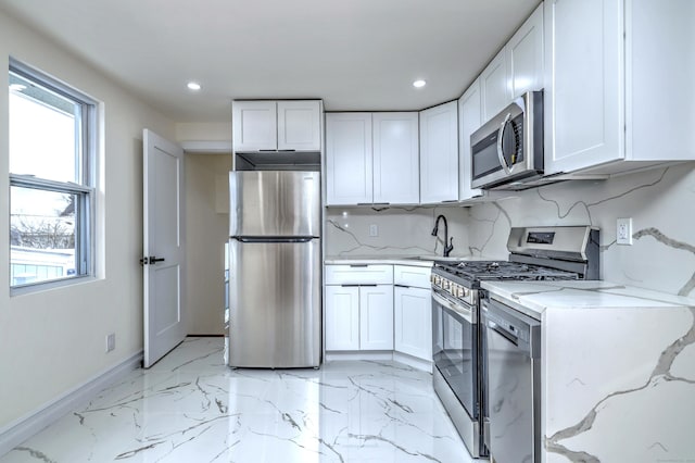 702 King St, Stratford, CT 06614 - kitchen with appliances with stainless steel finishes, white cabinets, healthy amount of natural light, recessed lighting, and light marble finish floors