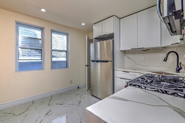702 King St, Stratford, CT 06614 - kitchen with freestanding refrigerator, light marble finish floors, baseboards, light stone counters, and white cabinetry