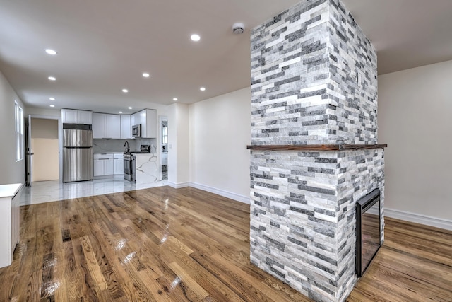 702 King St, Stratford, CT 06614 - unfurnished living room featuring light wood-style flooring, recessed lighting, baseboards, and a stone fireplace