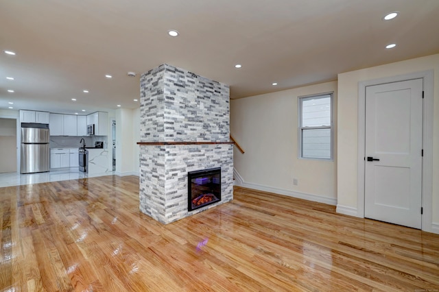 702 King St, Stratford, CT 06614 - unfurnished living room with recessed lighting, baseboards, light wood-type flooring, and a fireplace