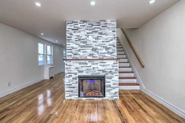 702 King St, Stratford, CT 06614 - unfurnished living room featuring radiator heating unit, stairway, wood finished floors, a tile fireplace, and recessed lighting