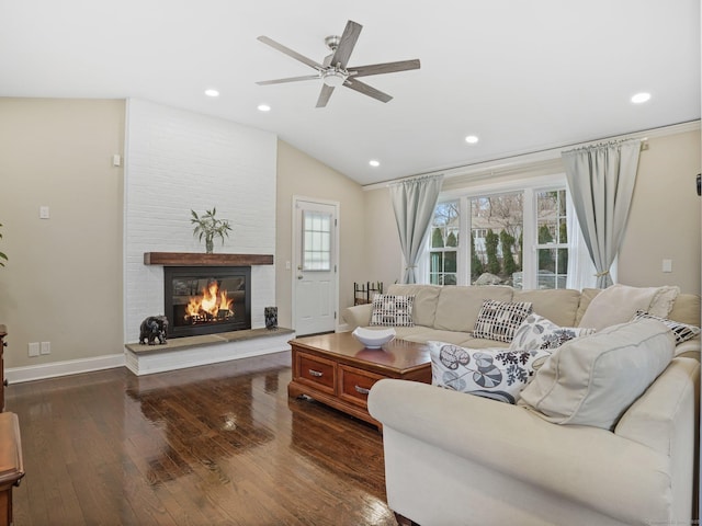 living room featuring lofted ceiling, a fireplace, dark wood-type flooring, and ceiling fan