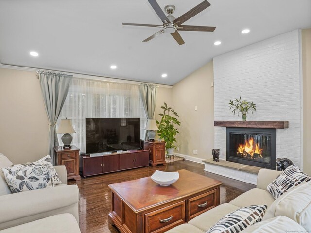 living room featuring dark hardwood / wood-style floors, ceiling fan, a fireplace, and vaulted ceiling