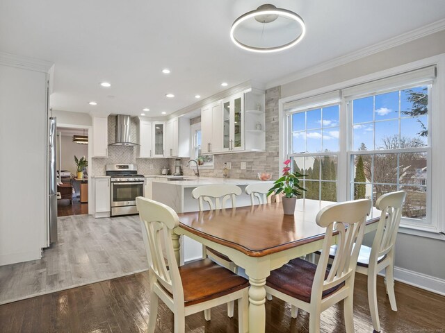 dining area featuring ornamental molding, sink, and light hardwood / wood-style floors