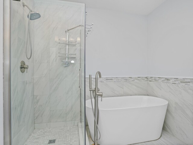 bathroom featuring shower with separate bathtub and tile walls