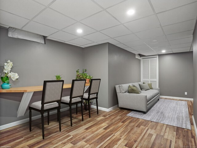 living room with a drop ceiling and wood-type flooring