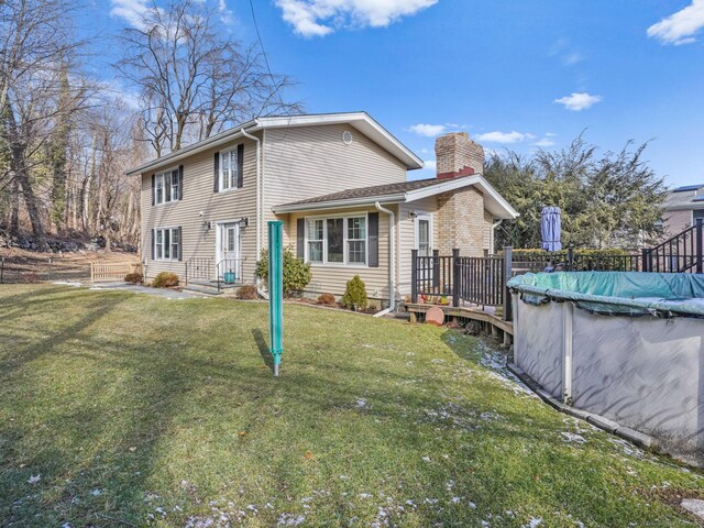 rear view of property featuring a covered pool and a lawn