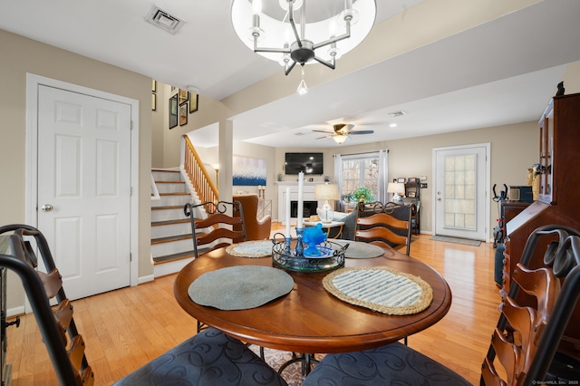 dining area with ceiling fan with notable chandelier and light hardwood / wood-style flooring