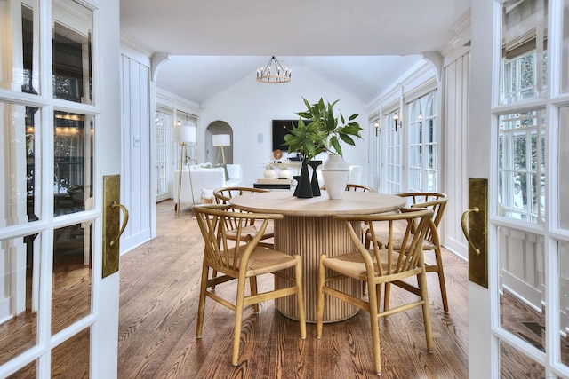 dining area with hardwood / wood-style flooring, french doors, lofted ceiling, and a chandelier