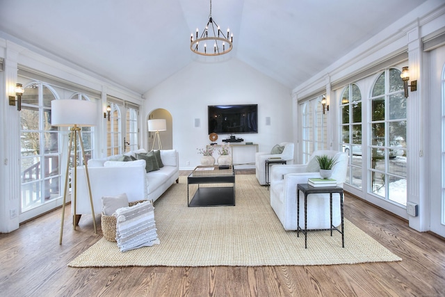 living room with lofted ceiling, wood-type flooring, french doors, and a chandelier