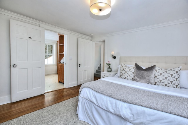 bedroom featuring hardwood / wood-style floors, crown molding, and connected bathroom