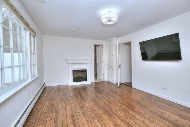 unfurnished living room with a baseboard heating unit and hardwood / wood-style floors