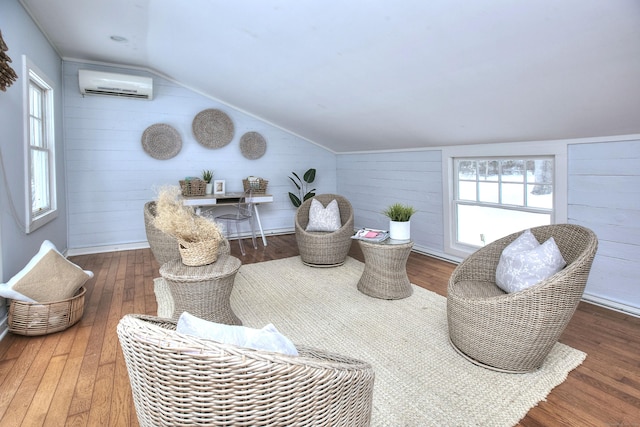 living area with dark wood-type flooring, lofted ceiling, a wall mounted air conditioner, and a healthy amount of sunlight