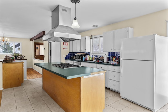 kitchen with white cabinetry, appliances with stainless steel finishes, a center island, and island range hood