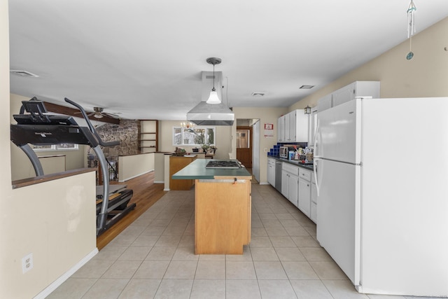 kitchen with white cabinetry, decorative light fixtures, a center island, light tile patterned floors, and appliances with stainless steel finishes