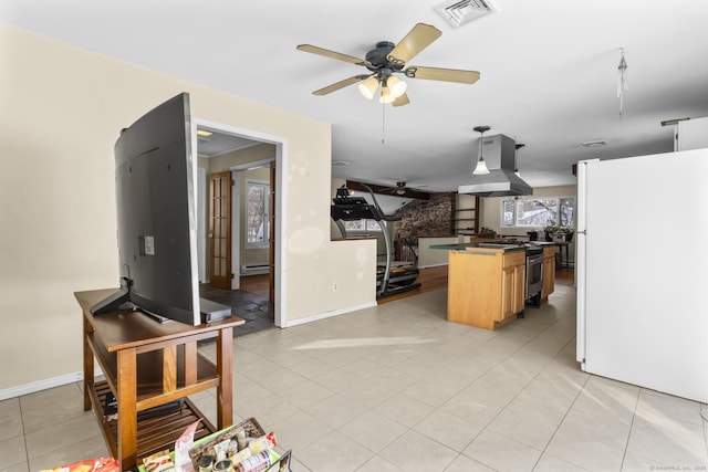 kitchen featuring stainless steel range with gas cooktop, a baseboard radiator, white refrigerator, island exhaust hood, and ceiling fan