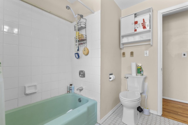 bathroom featuring tile patterned flooring, toilet, and tiled shower / bath