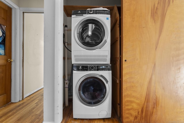 washroom featuring stacked washer / drying machine and hardwood / wood-style flooring