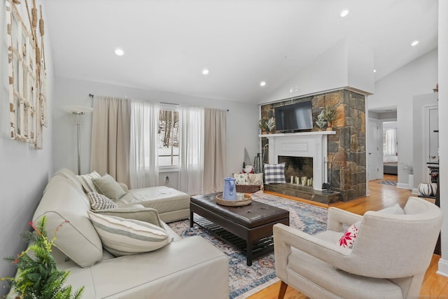 living room featuring light hardwood / wood-style flooring, a fireplace, and high vaulted ceiling