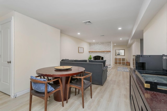 dining room with a brick fireplace and light hardwood / wood-style flooring