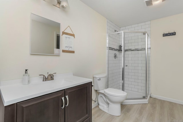 bathroom featuring vanity, toilet, a shower with shower door, and hardwood / wood-style floors