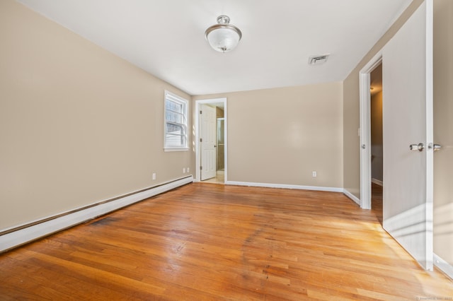 unfurnished room with light wood-type flooring and a baseboard heating unit