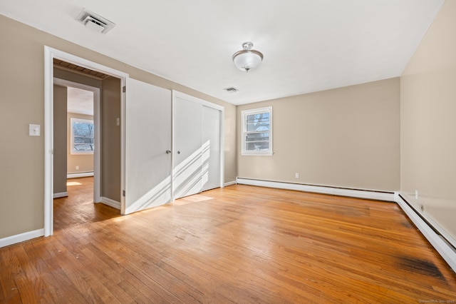 spare room featuring baseboard heating and light hardwood / wood-style flooring