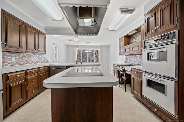 kitchen featuring pendant lighting, light tile patterned floors, double oven, a center island, and black electric stovetop