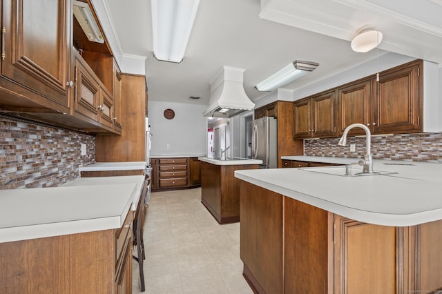 kitchen featuring premium range hood, a breakfast bar, sink, stainless steel fridge, and kitchen peninsula