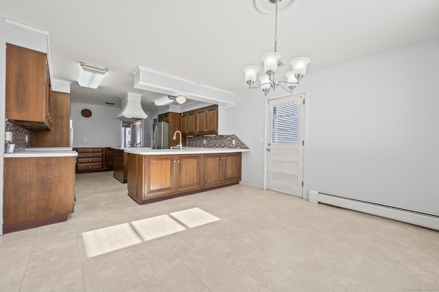 kitchen with stainless steel refrigerator, tasteful backsplash, sink, hanging light fixtures, and kitchen peninsula