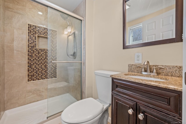 bathroom with vanity, a shower with shower door, and toilet