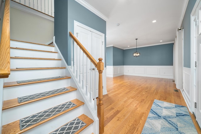 stairs with hardwood / wood-style floors and crown molding