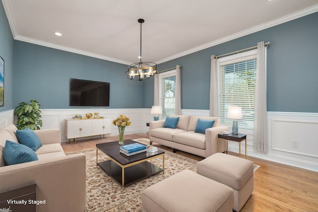 living room with ornamental molding, a chandelier, and light hardwood / wood-style flooring