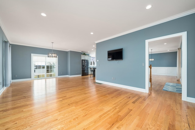 unfurnished living room featuring crown molding, a notable chandelier, and light hardwood / wood-style floors