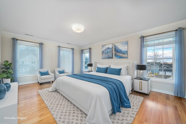 bedroom with multiple windows, hardwood / wood-style flooring, and ornamental molding