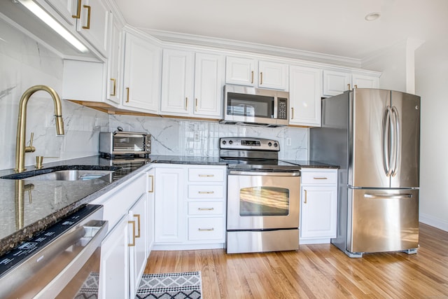 kitchen with stainless steel appliances, white cabinetry, and a sink