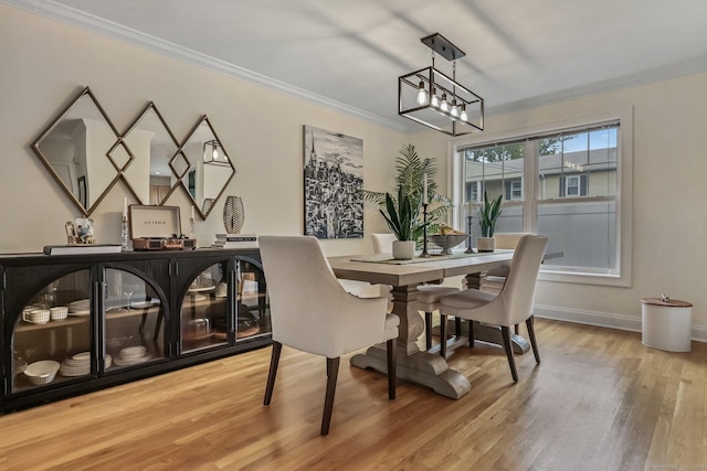 dining space featuring a notable chandelier, crown molding, light wood-style flooring, and baseboards