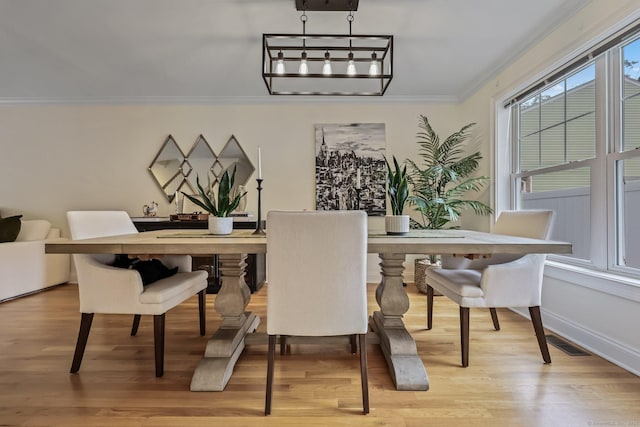 dining area featuring light wood-style floors, visible vents, crown molding, and baseboards