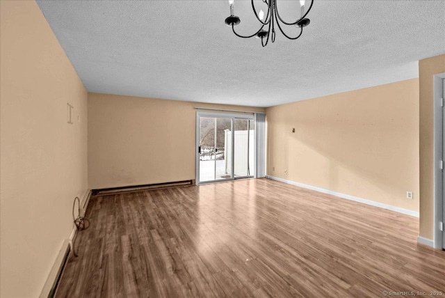 empty room with hardwood / wood-style floors, a textured ceiling, and an inviting chandelier