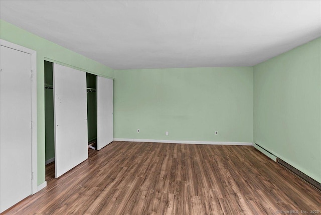 unfurnished bedroom featuring dark hardwood / wood-style floors and a baseboard heating unit