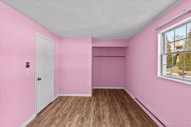 unfurnished bedroom with a baseboard radiator, hardwood / wood-style floors, a closet, and a textured ceiling