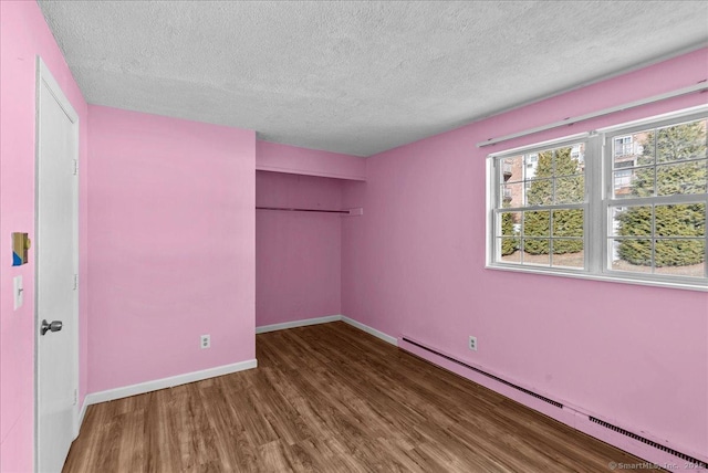 unfurnished bedroom featuring a baseboard radiator, a textured ceiling, dark hardwood / wood-style flooring, and a closet