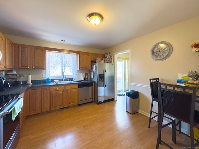 kitchen featuring appliances with stainless steel finishes, sink, and light hardwood / wood-style flooring