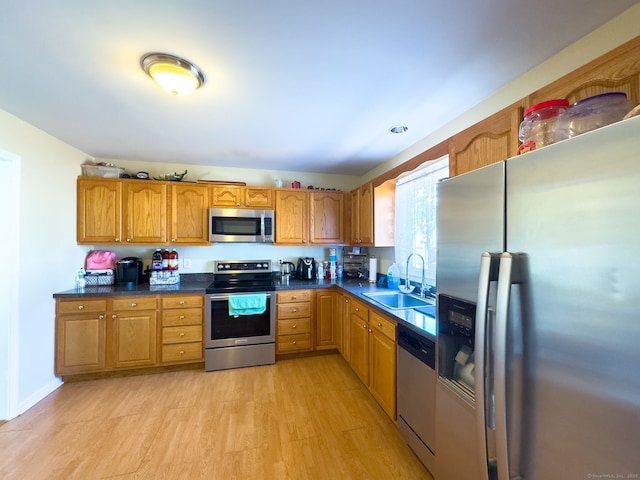 kitchen featuring appliances with stainless steel finishes, sink, and light hardwood / wood-style flooring