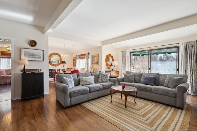 living room with dark wood-type flooring, plenty of natural light, a chandelier, beamed ceiling, and baseboards